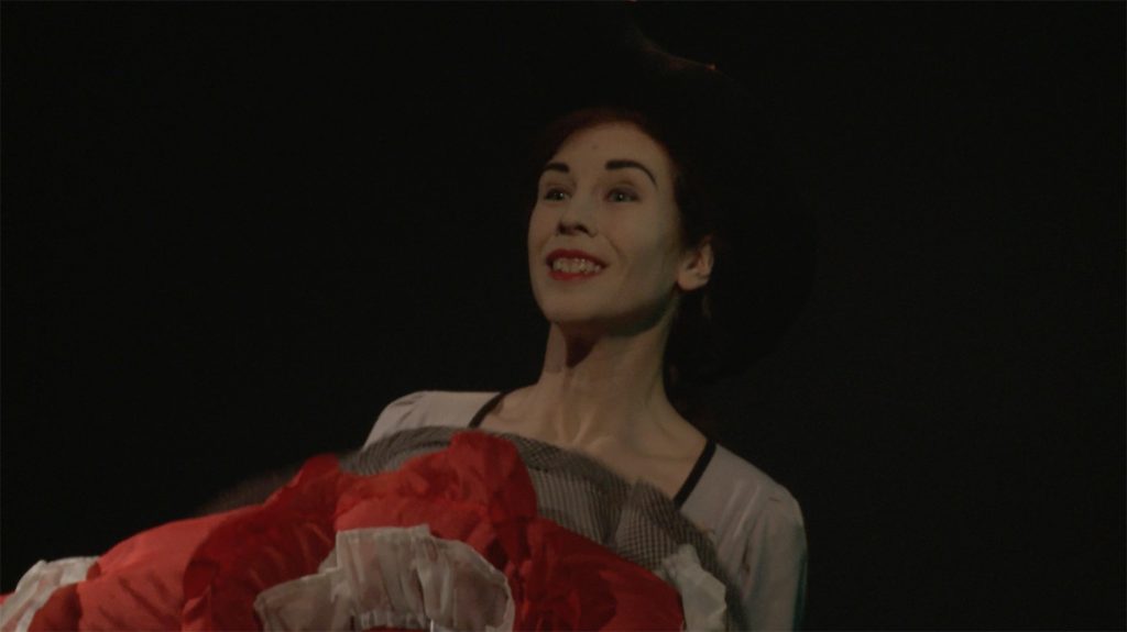 Video still from artwork where artist Maria Norrman interprets and invokes dance artist Jane Avril.
The artist in a dancing pose, dressed in cancan clothing.